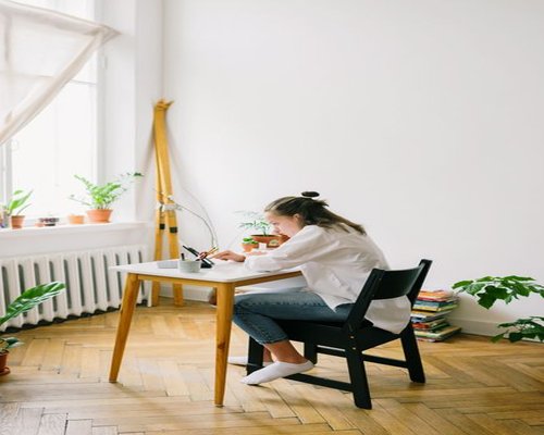 Student attending an online class on a tablet with natural light