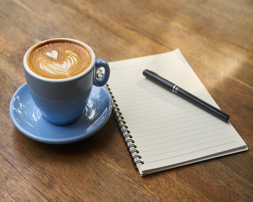Coffee cup and notebook on a wooden desk